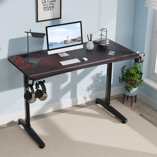 This is an image of the Black GIP 47" Gaming Desk in a realistic setting with a computer on top and other peripherals.